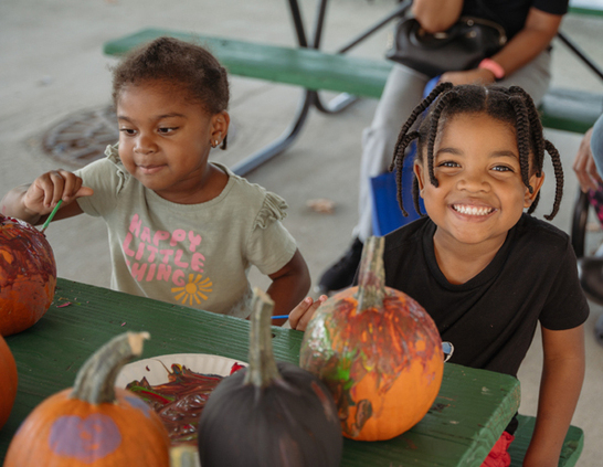 two children sitting at a table with pumpkins