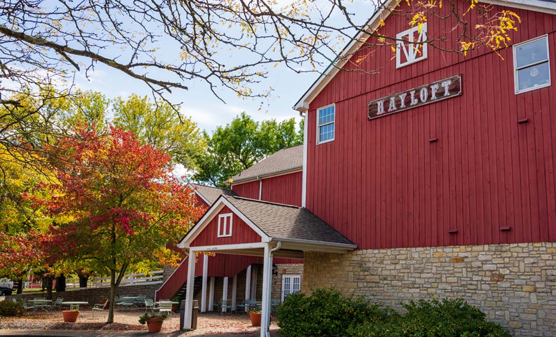 a red barn with trees and a white canopy