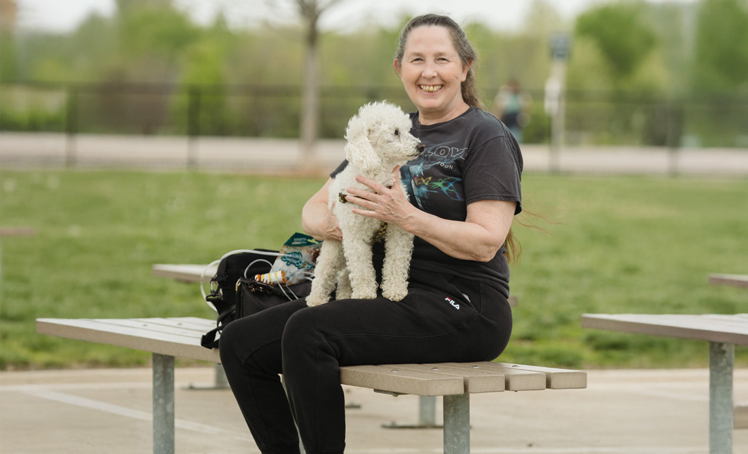 a woman sitting on a bench holding a dog