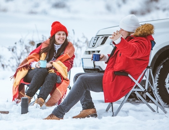 Couple camping in the snow by a truck