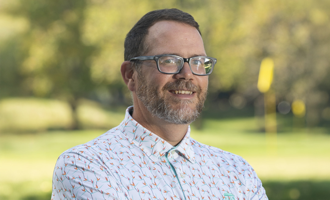 a man in glasses holding a golf club
