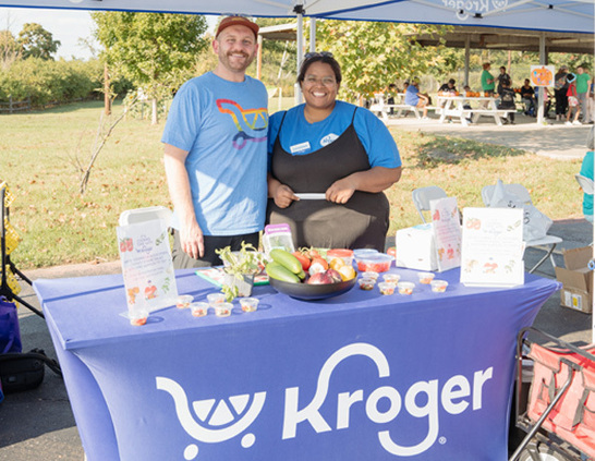 a man and woman standing next to a table with food