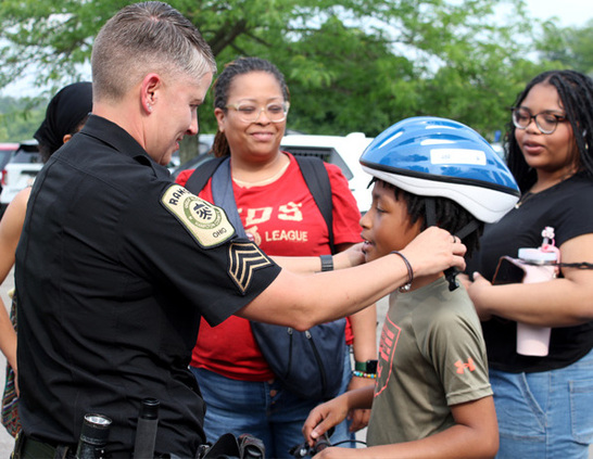 a police officer fixing a boy's helmet