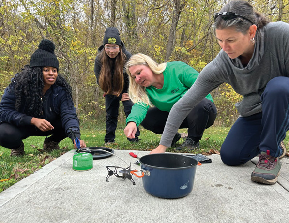 a group of women outside by a pot and a fire